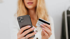 Frau mit iPhone und Kreditkarte