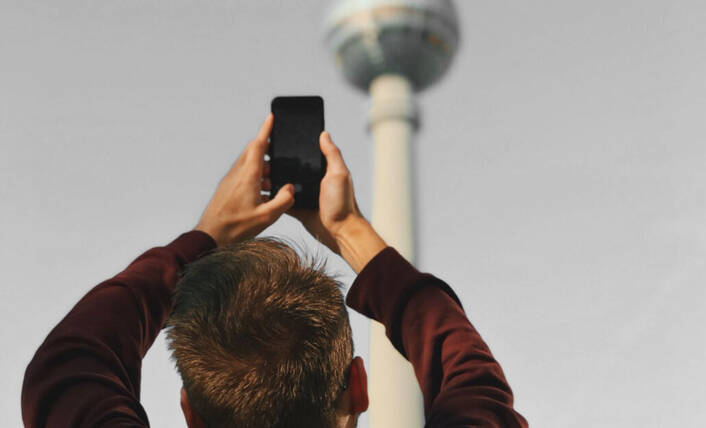 Visual Intelligence erkennt Gebäude & Wahrzeichen (Foto: Valeriya Kobzar / pexels) Mann richtet iPhone auf Berliner Fernsehturm