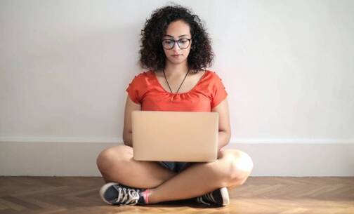 Selbständigkeit und ortsunabhängig arbeiten heisst, auch mal am Boden zu sitzen. Digitale Nomadin arbeitet sitzend am Boden.