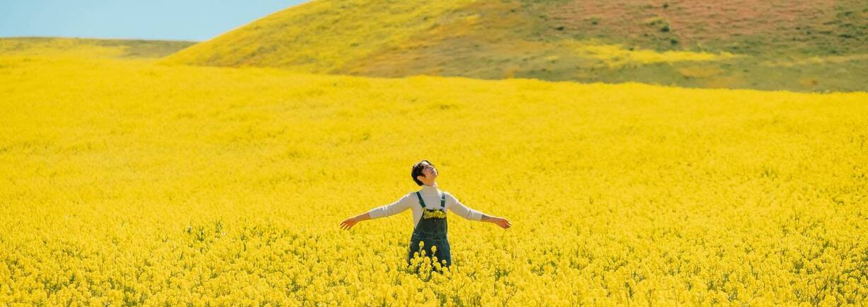 Eine junge Frau geniesst ihre Freizeit in einem Rapsfeld.