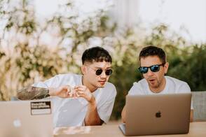 Zwei Digitalnomaden arbeiten im Coworking mit MacBook. MacBook als technische Ausrüstung für die ortsunabhängige Arbeit