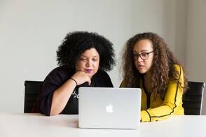 Zwei Frauen sitzen vor einem MacBook