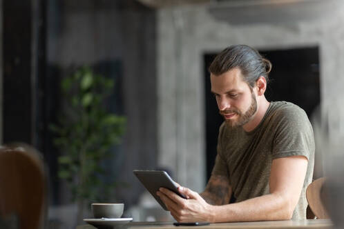 Ein Mann sitzt mit iPad am Tisch