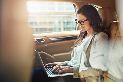 Eine Frau sitzt mit Mac in einem Auto