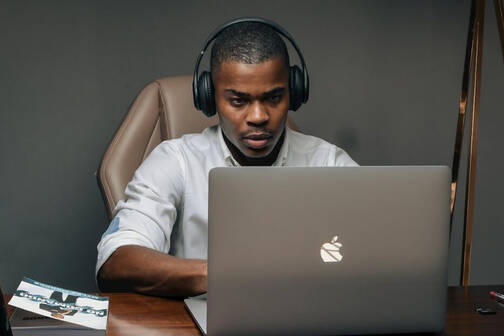 Ein Mann arbeitet daheim mit dem MacBook seines Arbeitgebers, das über MDM verwaltet wird.