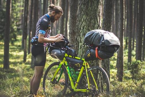 Mit der Komoot App kannst du auf dem Fahrrad navigieren Ein Bikepacker orientiert sich auf seiner Route bei einer Pause