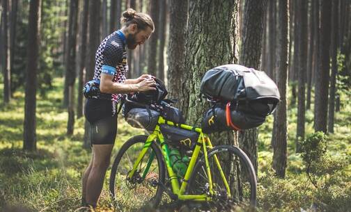 Mit der Komoot App kannst du auf dem Fahrrad navigieren Ein Bikepacker orientiert sich auf seiner Route bei einer Pause