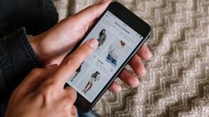 Online Shops nutzen First-Party-Cookies für ein besseres Nutzererlebnis Eine Frau surft auf ihrem iPhone in einem Online-Shop