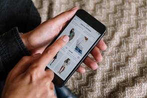 Online Shops nutzen First-Party-Cookies für ein besseres Nutzererlebnis Eine Frau surft auf ihrem iPhone in einem Online-Shop