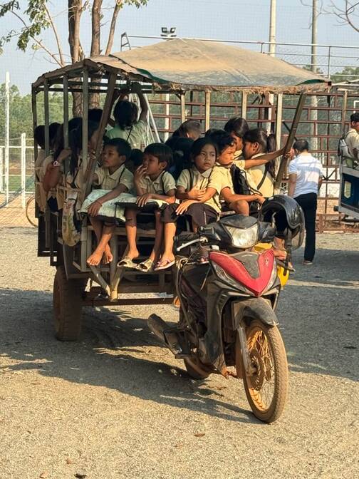 In Kambodscha werden Kinder mit einem Motorradanhänger nach Hause gefahren. Transport der Kinder in Kambodscha von der Schule nach Hause