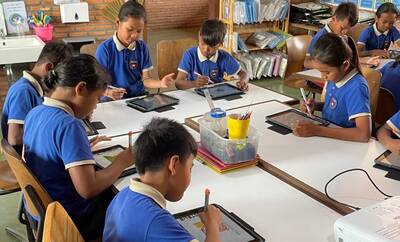 Lernende in blauer Uniform zeichnen auf iPad Schülerinnen und Schüler beim Zeichnen – Hilfswerk Smiling Gecko