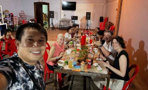 Das ganze Smiling Gecko Team geniesst das Essen Sam nimmt ein Selfie auf mit dem Team am Tisch im Hintergrund