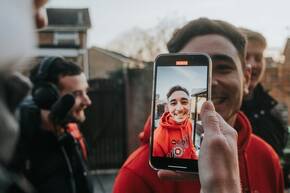 Ein junger Mann wird mit iPhone gefilmt Mit iPhone ein Video aufnehmen