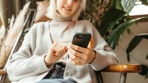 Frau mit iPhone nutzt Apple Intelligence Apple Intelligence bringt Effizienz und Freude
