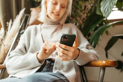 Frau mit iPhone nutzt Apple Intelligence Apple Intelligence bringt Effizienz und Freude