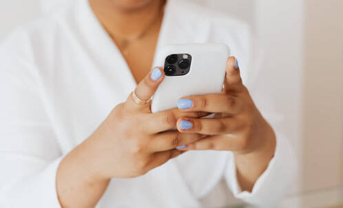Frau mit blauen Fingernägeln beim Gaming auf dem iPhone