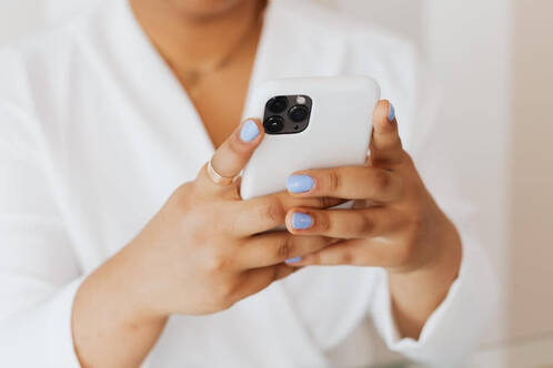 Frau mit blauen Fingernägeln beim Gaming auf dem iPhone
