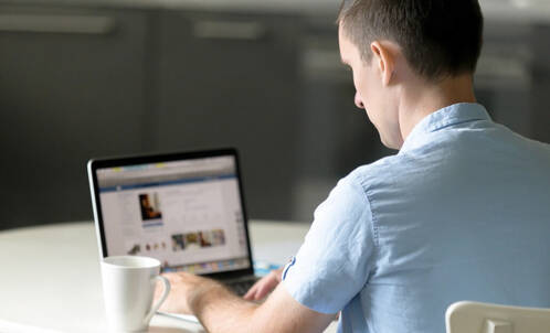 Mann sitzt vor MacBook