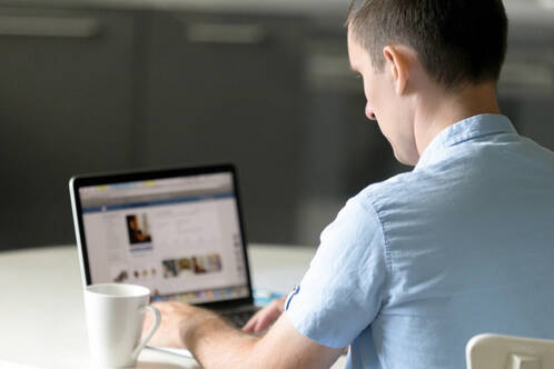 Mann sitzt vor MacBook