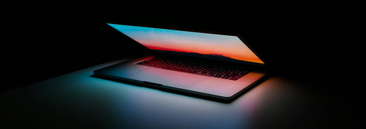 MacBook beleuchtet Tischplatte MacBook leuchtet leicht aufgeklappt in der Dunkelheit