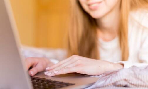 Junge Frau sitzt vor ihrem MacBook Frau bewegt Cursor auf MacBook
