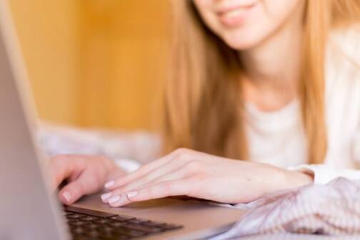 Junge Frau sitzt vor ihrem MacBook Frau bewegt Cursor auf MacBook