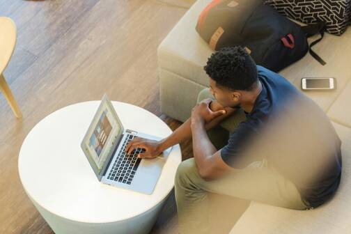 MDM-Einschränkungen schützen bei Remote Arbeit Mann sitzt im Coworking mit MacBook