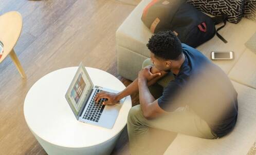 Mann sitzt im Coworking mit MacBook