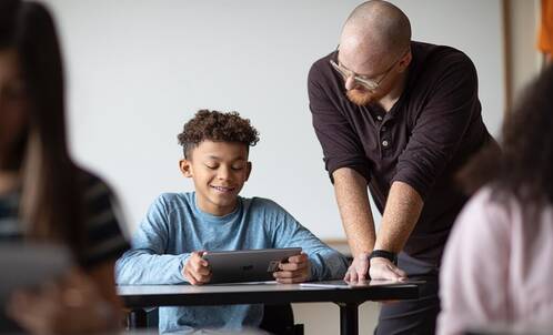 Lehrperson hilft Schüler mit iPad