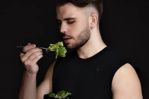 Mann mit Ultrahuman Ring Air am Finger isst Salat