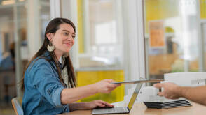 Lehrerin reicht iPad an andere Lehrperson