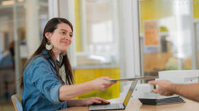Lehrerin reicht iPad an andere Lehrperson