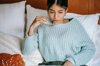 Junge Frau mit Kreditkarte schaut in Bildschirm