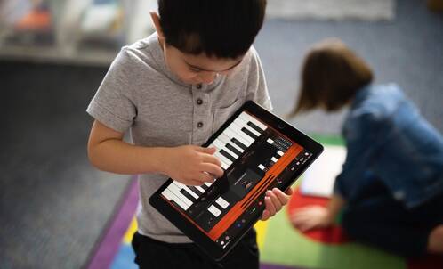Junge spielt Piano auf iPad in der Schule