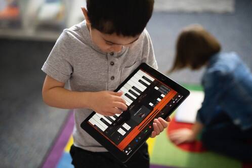 Junge spielt Piano auf iPad in der Schule