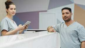 Zwei Mitarbeitende stehen am Empfang einer Arztpraxis