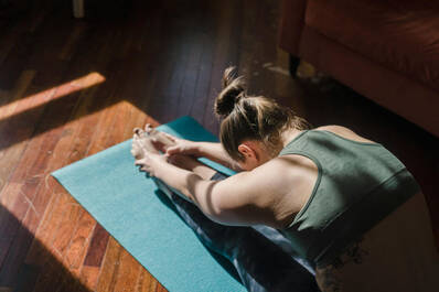 Stretching zu Hause auf der Matte (Foto: Tim Samuel / pexels) Frau beim Stretching auf Yogamatte