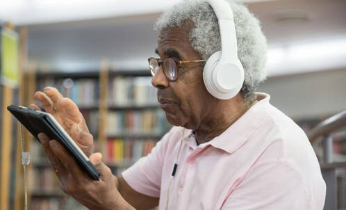 Senior mit AirPods Max und iPad