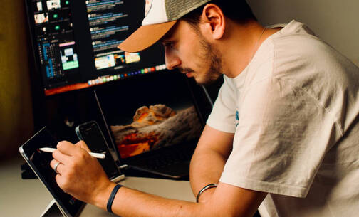 Mann arbeitet mit iMac, iPad und iPhone