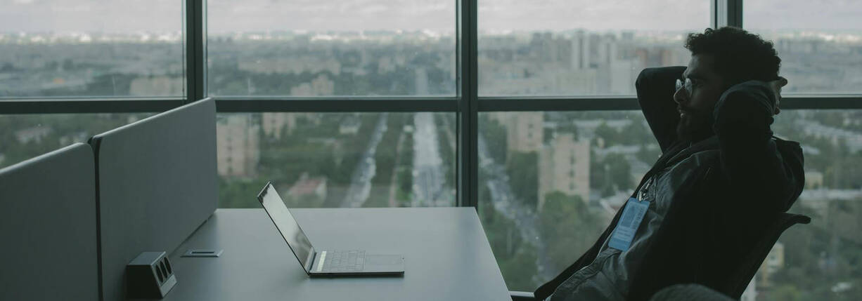 Mann sitzt vor MacBook in Büro