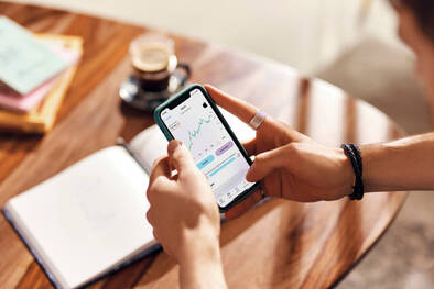 Hände halten iPhone mit Finanzen-App