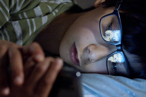 Junge mit iPhone im Bett