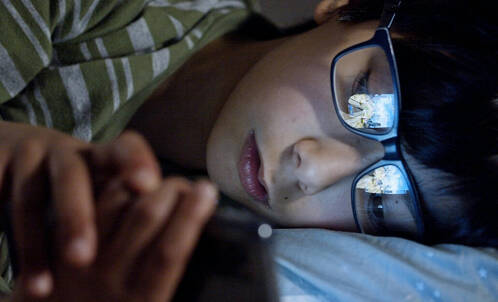 Junge mit iPhone im Bett