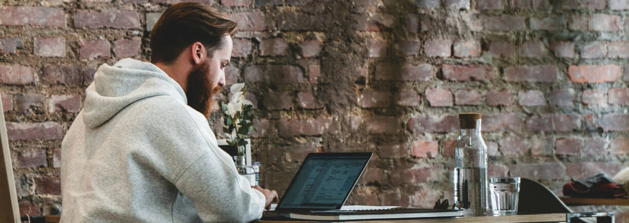 Mann sitzt im Café vor MacBook