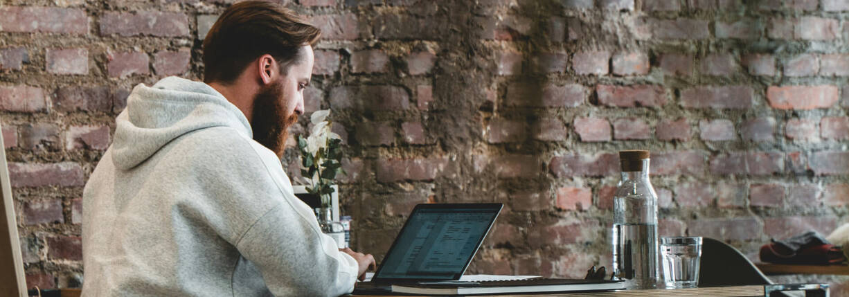 Mann sitzt im Café vor MacBook