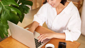 Frau mit MacBook und Kaffee