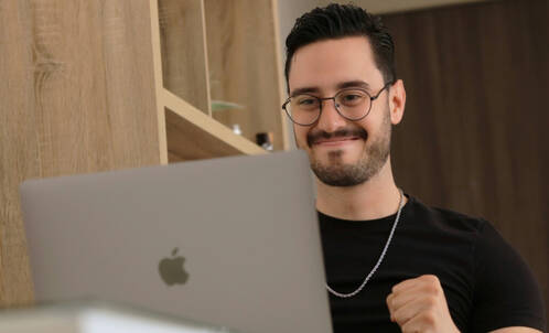 Mann vor MacBook freut sich 