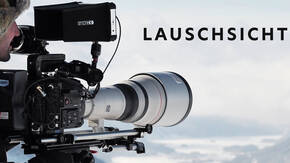 Professionelle Filmkamera mit Teleobjektiv vor bewölktem Himmel – Lauschsicht