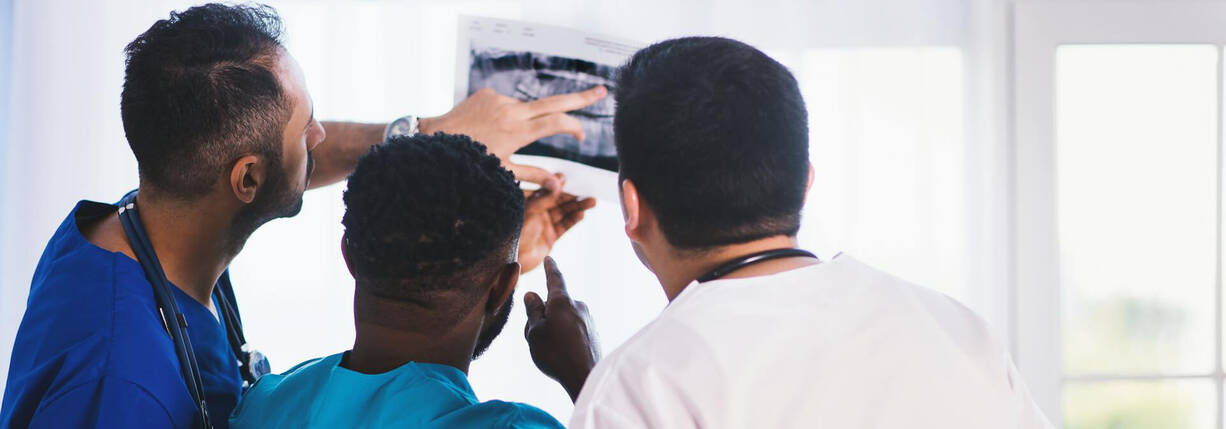 Drei Ärzte prüfen ein Röntgenbild