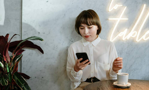 Frau im Café prüft ihr iPhone